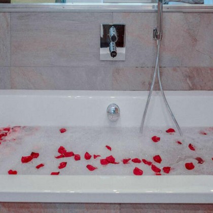 Romantic room with bath salts, soap bomb, petals, chocolates, champagne and detail